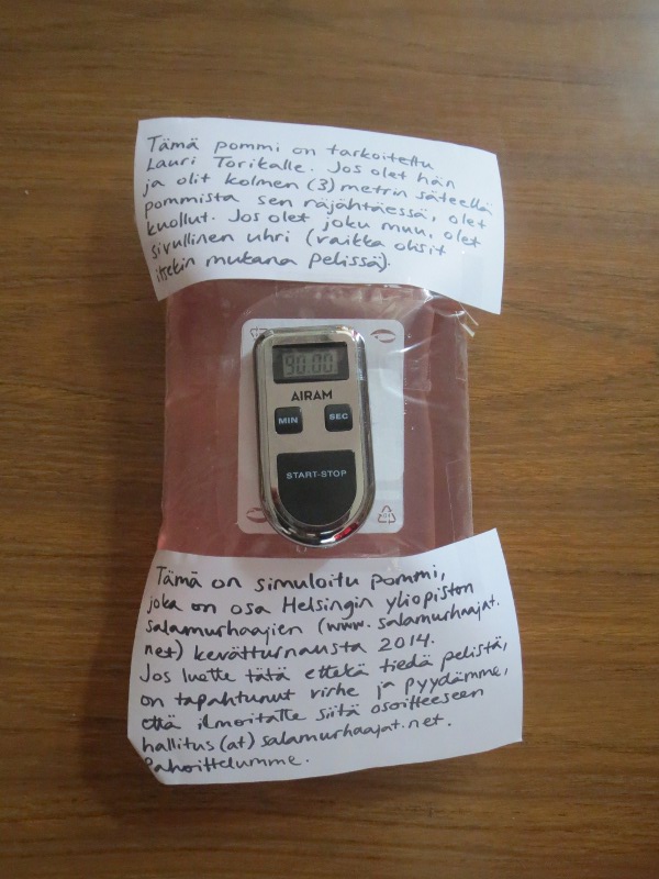 Kuva feikkipommista, jonka päällä näkyy viesti. / A picture about a fake bomb, with a message attached on top.